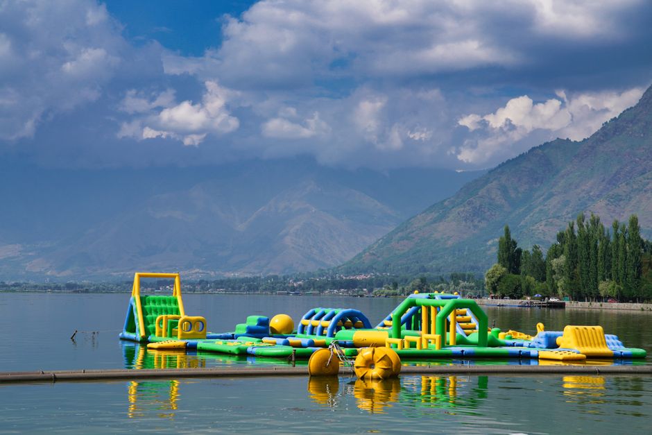 Vibrant inflatable obstacle course on a tranquil alpine lake surrounded by mountains.