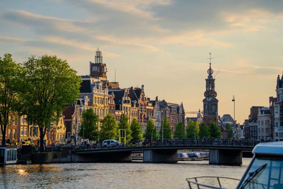 Charming view of Amsterdam canals with historic buildings and bridge at sunset.