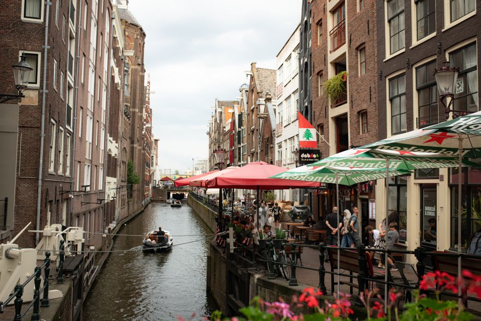 Picturesque canal in Amsterdam with lively cafes and people enjoying the day.