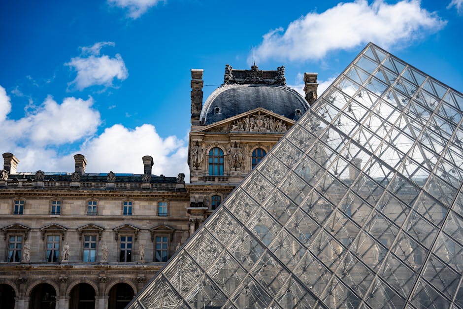 Stunning view of the Louvre Pyramid and historic building in Paris with clear blue skies.