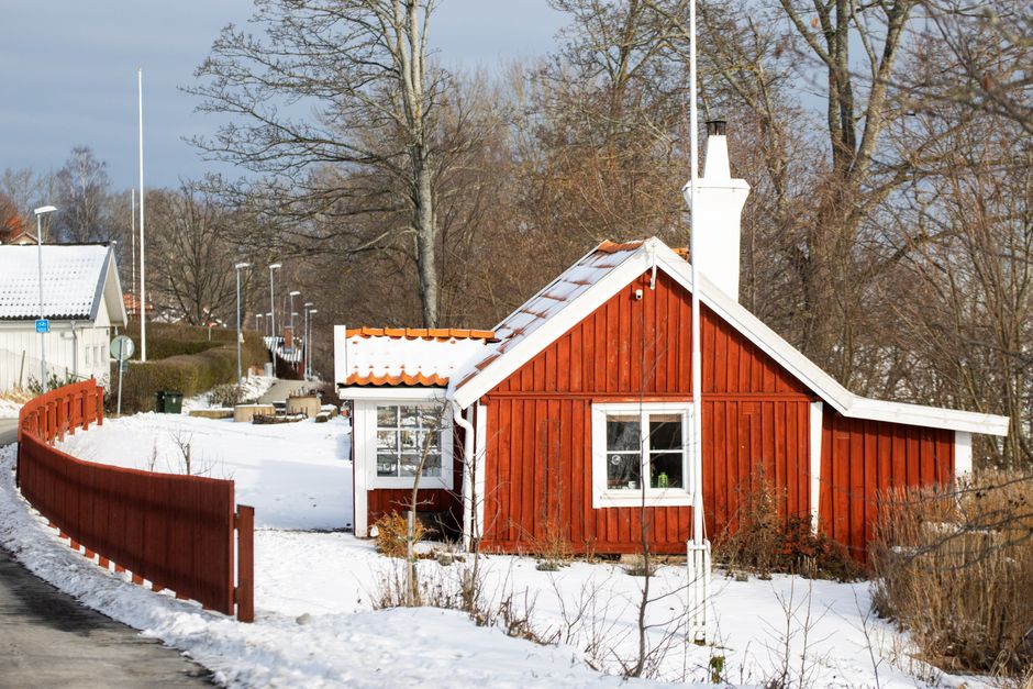 A picturesque red cottage in a snowy Jönköping setting, capturing Swedish winter charm.