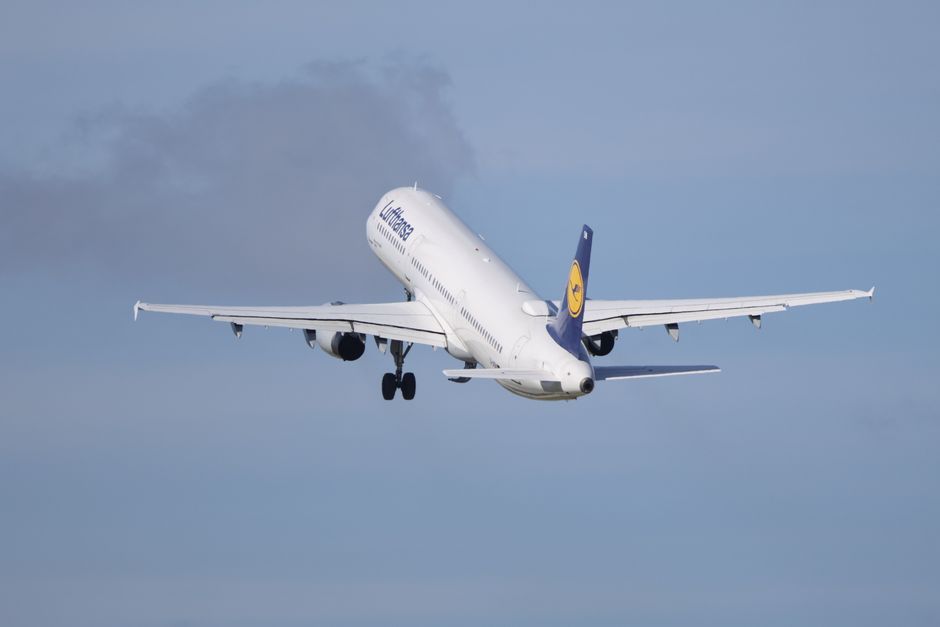 A Lufthansa Airbus A320 aircraft taking off into the clear blue sky.