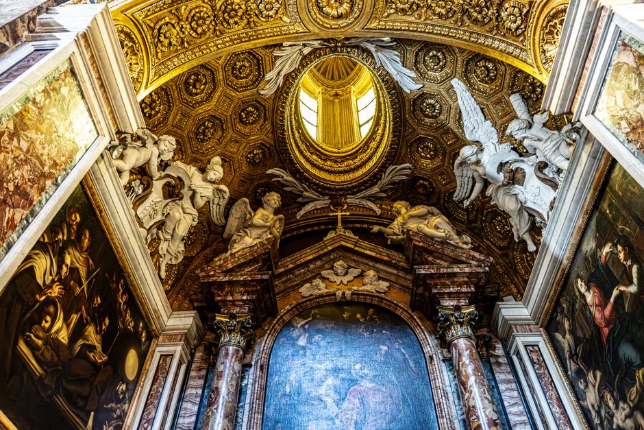 Detailed view of a Baroque church ceiling in Roma, showcasing intricate sculptures and paintings.