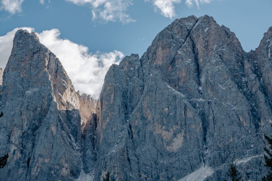 Stunning view of rocky Dolomites peaks against a blue sky with clouds, ideal for nature photography enthusiasts.