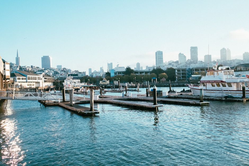 Vibrant city skyline with high-rise buildings and boats at a serene waterfront pier.