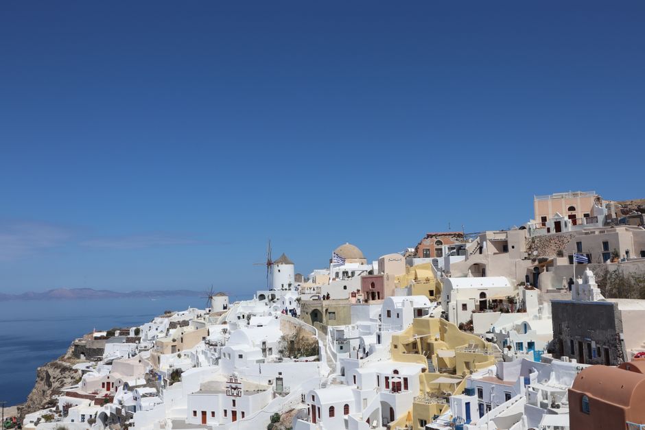 Explore the iconic whitewashed architecture of Oia, Santorini under a clear blue sky.