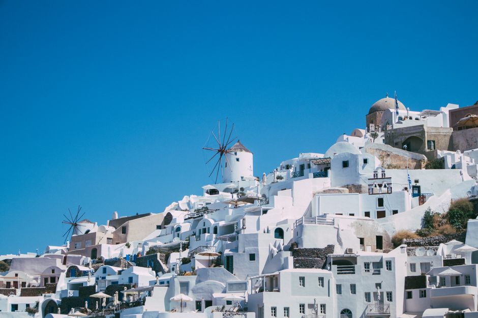 Capture of Santorini's iconic white buildings and windmills under a clear blue sky.