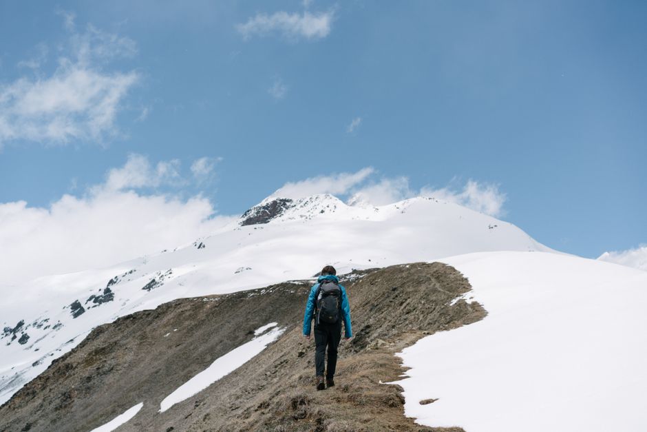 Man hiking in snowy mountains, capturing adventure and wanderlust in a stunning blue-sky setting.