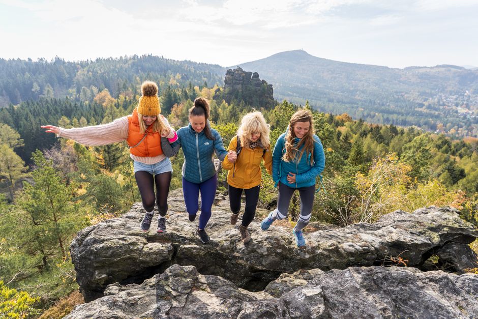 Four friends enjoying a joyful hike on Oybin's rocky terrain with scenic views.