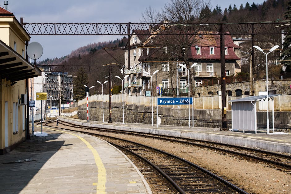 Scenic view of Krynica-Zdrój train station surrounded by mountains and architecture.