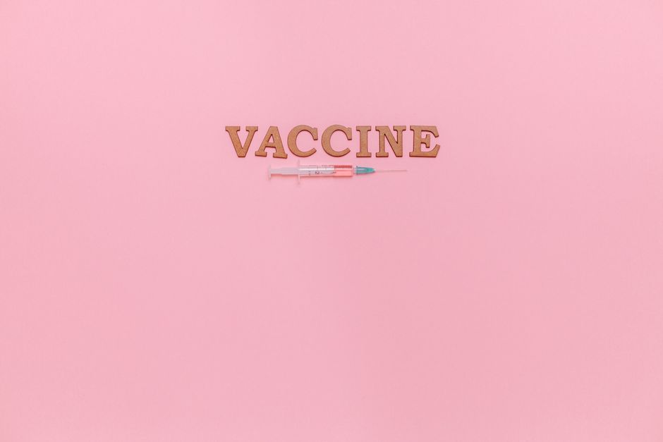 A vaccine syringe and word 'VACCINE' on a pink background, ideal for healthcare themes.