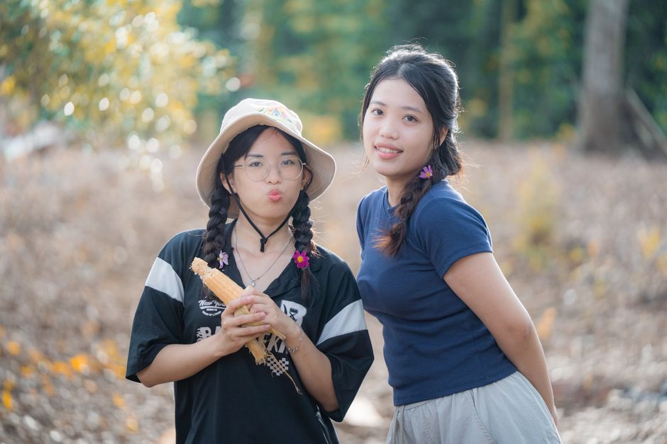 Two young women enjoying a sunny day outdoors with cheerful expressions and playful hairstyles.