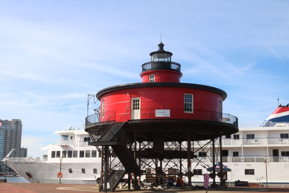 Red historic lighthouse at Baltimore's Inner Harbor with clear skies.